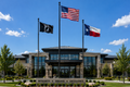 Building exterior with flags and 'Integrity Service Excellence' sign against a blue sky.
